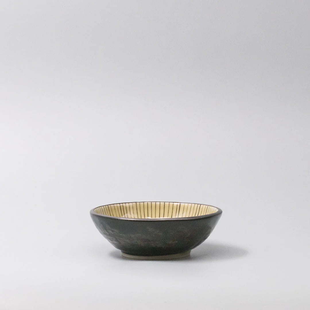 Black ceramic bowl with gold interior on a light gray background