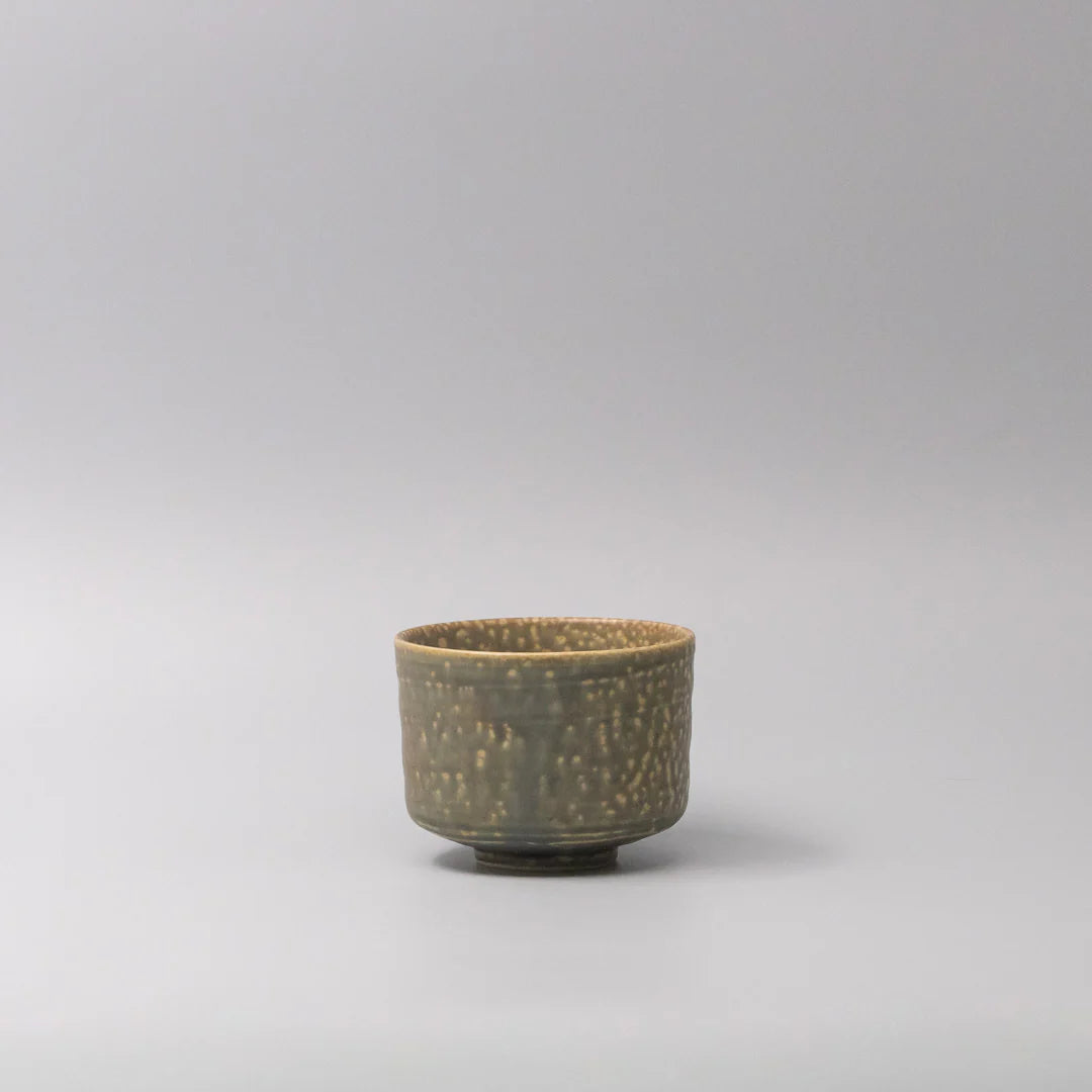 Small ceramic cup with textured surface on a light gray background