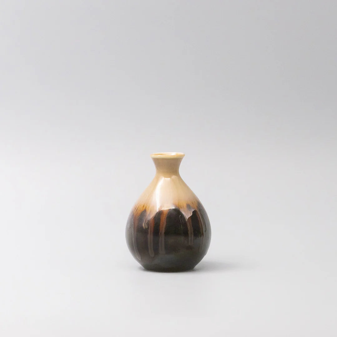 Small ceramic vase with a two-tone design on a light gray background