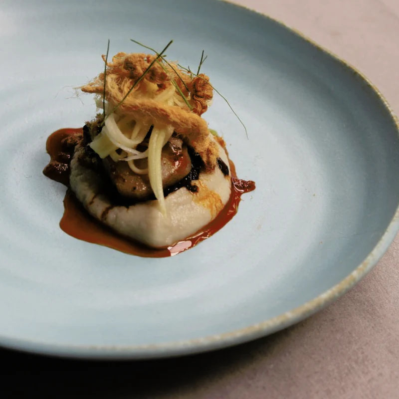 Delicate dish on a light blue plate with a textured surface