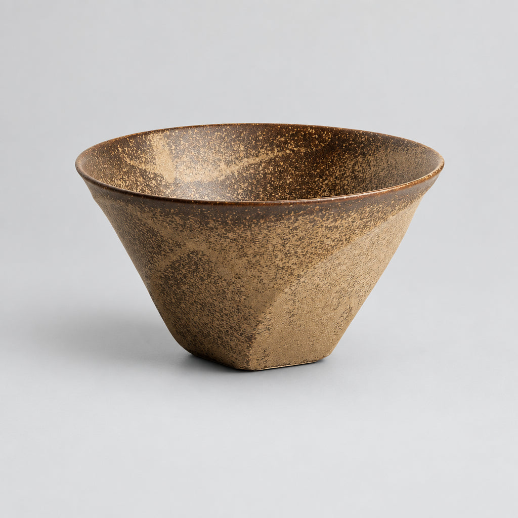 A handmade ceramic bowl with a textured, speckled glaze in earthy brown and beige tones, shown on a clean white background.