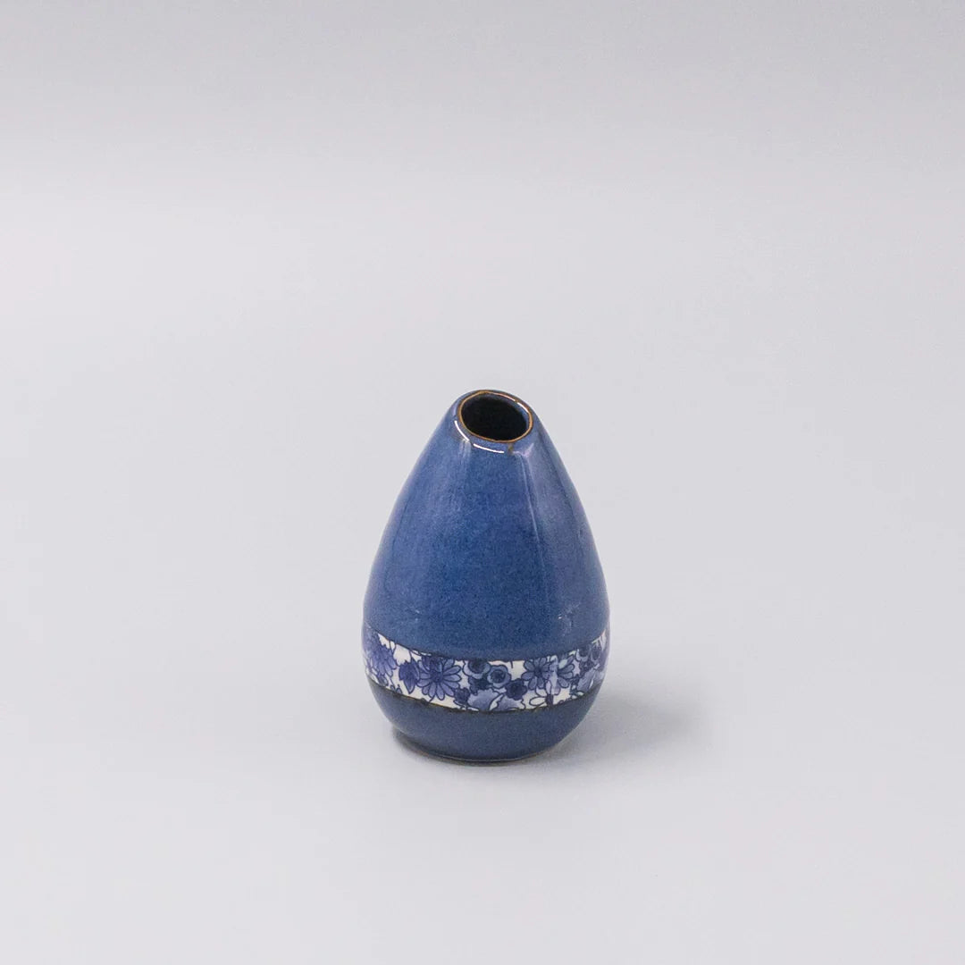 Blue ceramic vase with decorative pattern on a light gray background