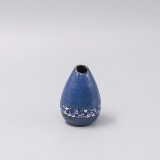 Blue ceramic vase with decorative pattern on a light gray background