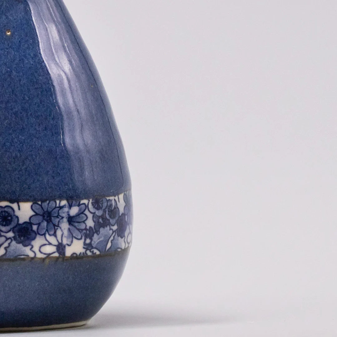 Ceramic vase with blue glaze and floral pattern on a white background