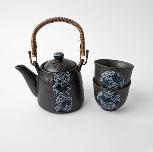Black ceramic teapot with wicker handle and matching cups on a white background