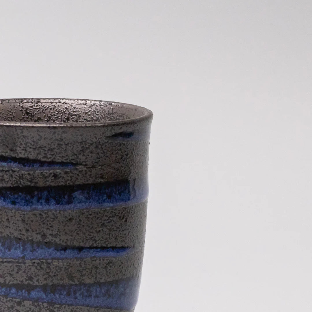 Close-up of a ceramic cup with textured design on a light gray background