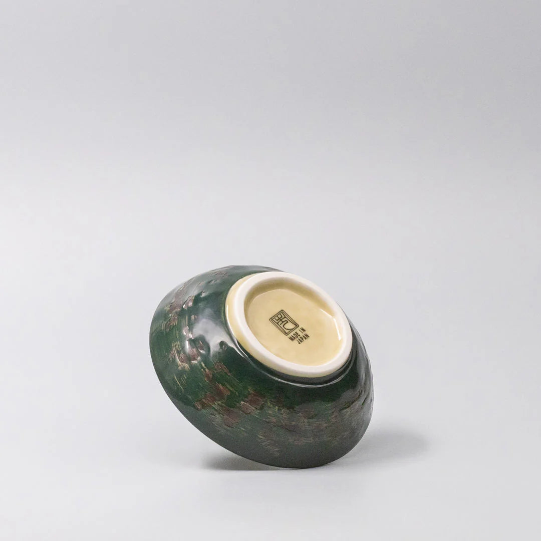 Green ceramic bowl with a white interior on a light gray background