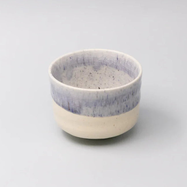 Small ceramic bowl with a blue and white glaze on a light gray background