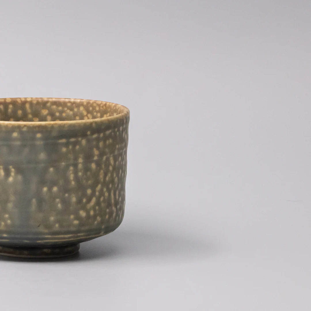 Ceramic cup with speckled glaze on a gray background