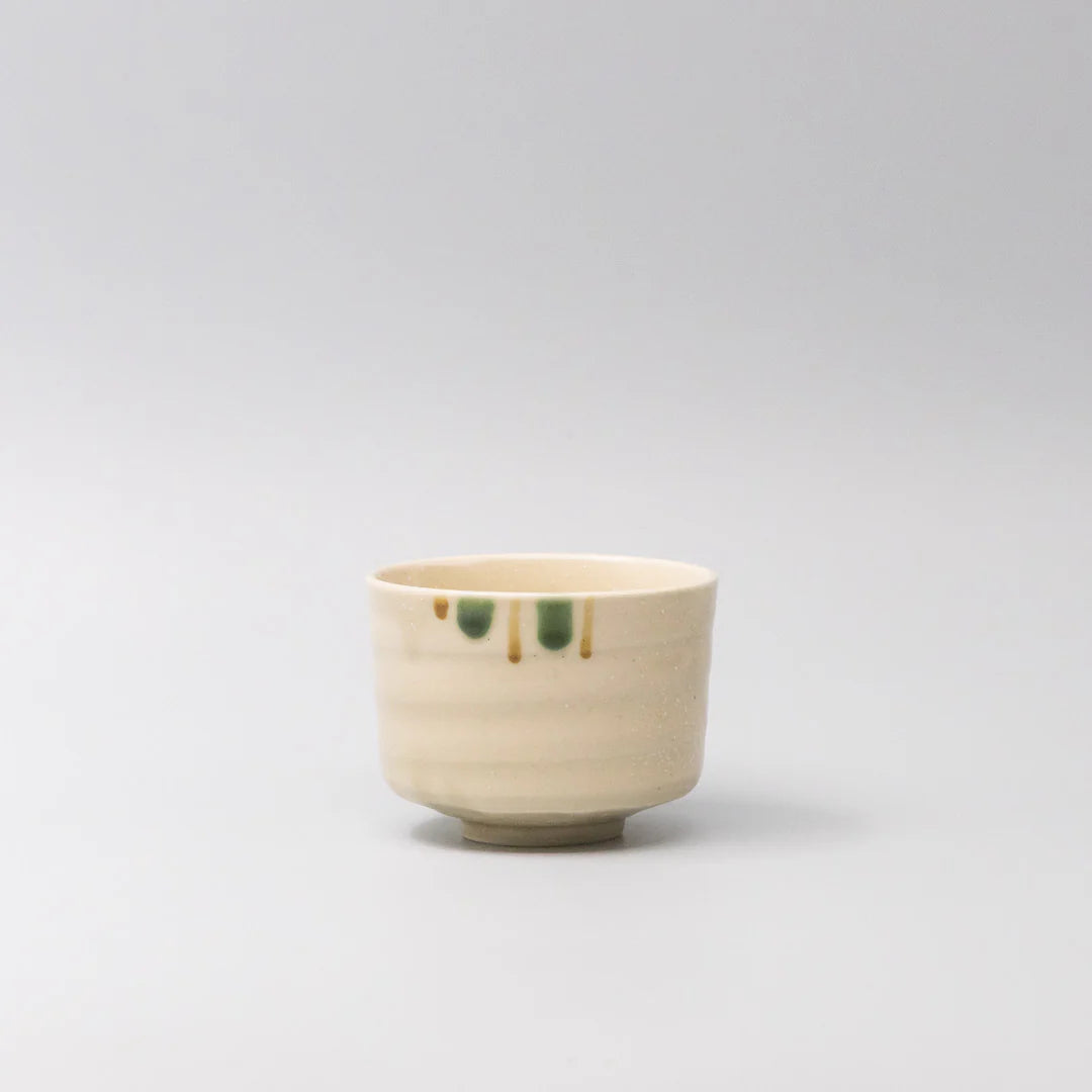 Small ceramic cup with green accents on a light gray background