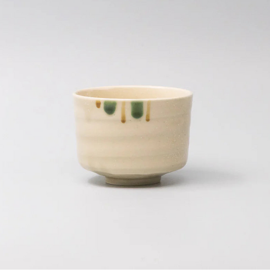 Small ceramic cup with green accents on a light gray background
