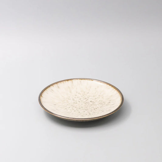 Round ceramic plate with textured surface on a light gray background