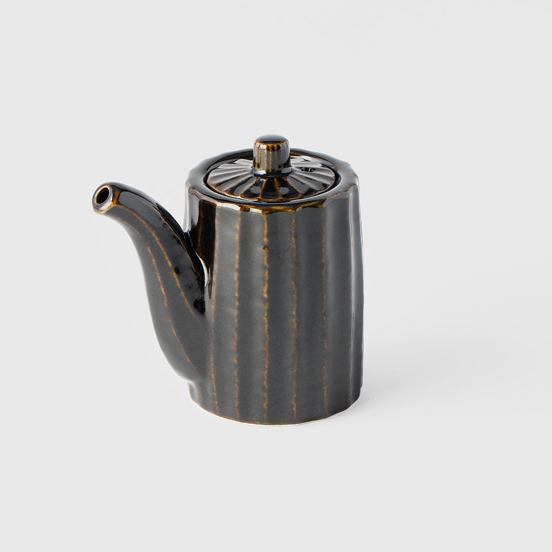 Black ceramic teapot with decorative patterns on a light gray background