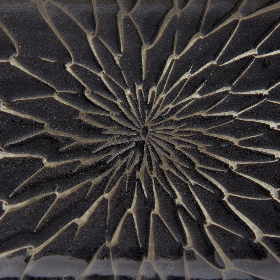 Close-up of a textured black surface with a starburst pattern