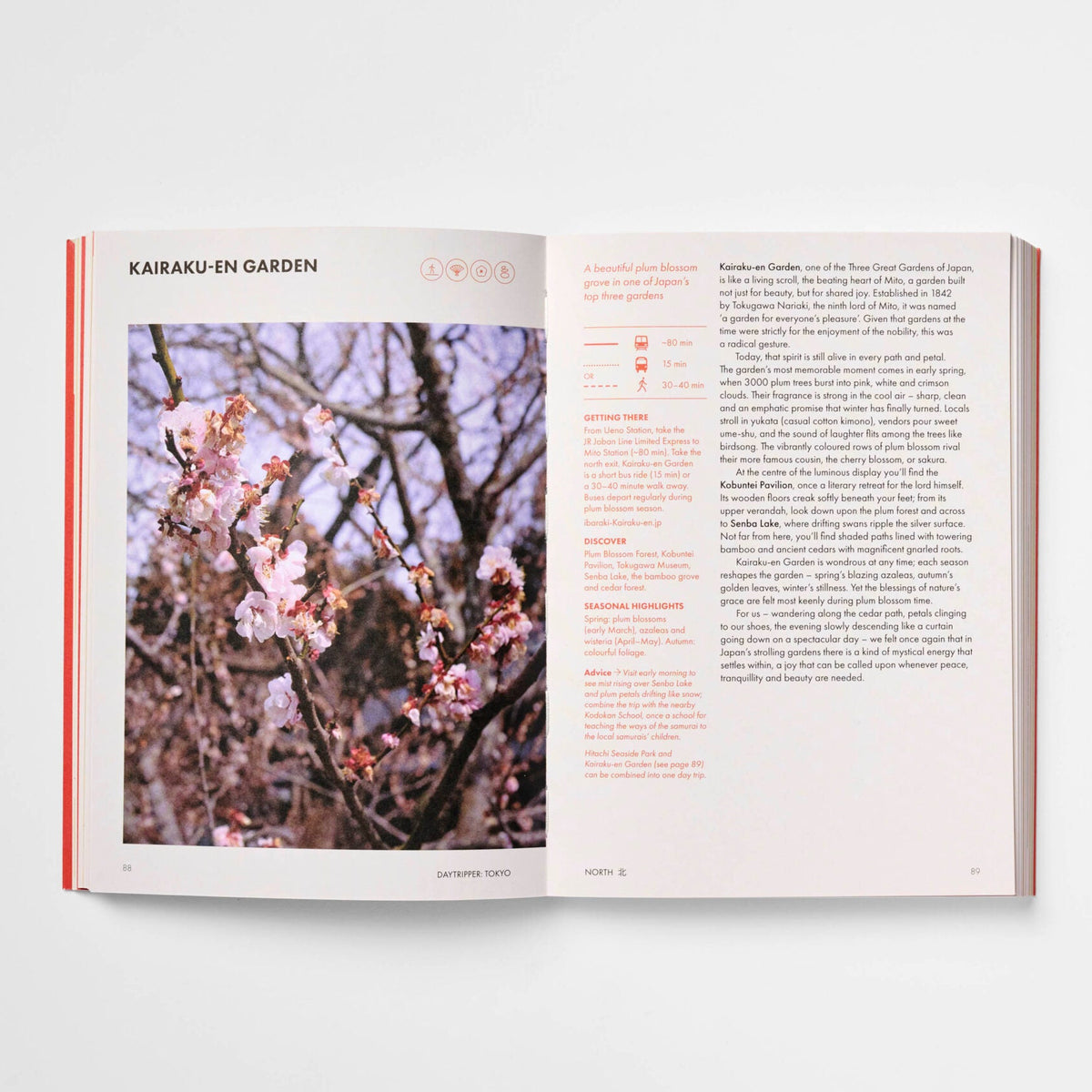 An open book or magazine laid flat on a light gray background, showing a page titled 'KARAKI OR GARDEN' with a photograph of pink blossoms on a tree and columns of text on the right page.