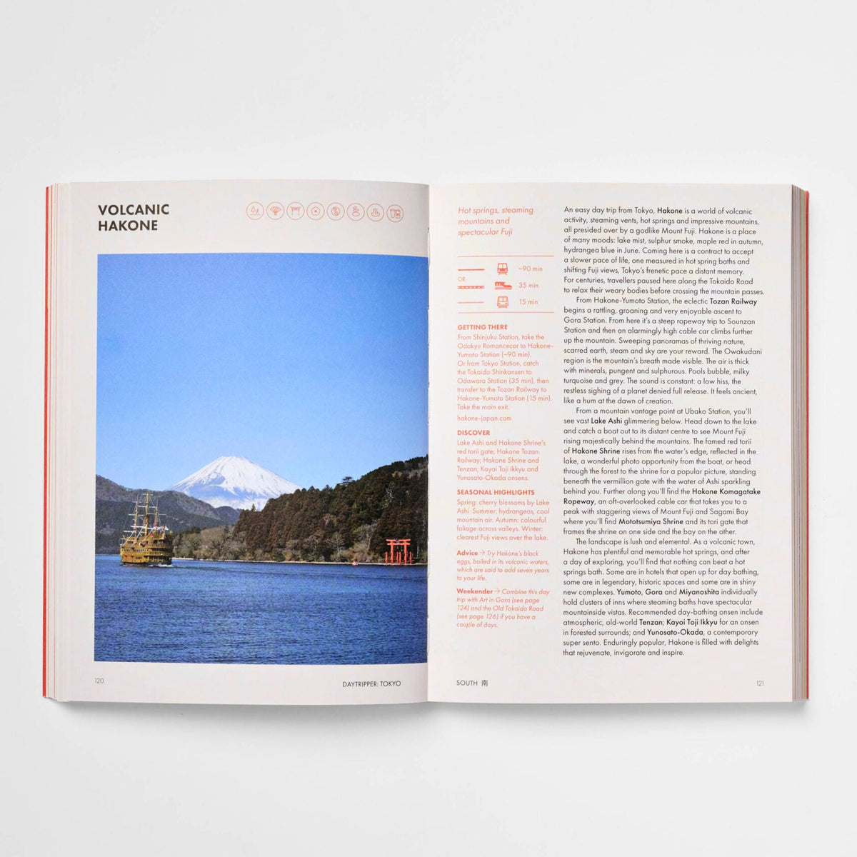 An open book or magazine spread on a light gray background, showing a landscape photograph of Mount Fuji over water on the left page and text columns on the right page.