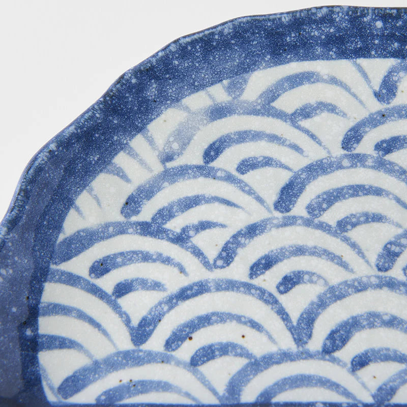 Close-up of a ceramic plate with blue wave pattern on a white background