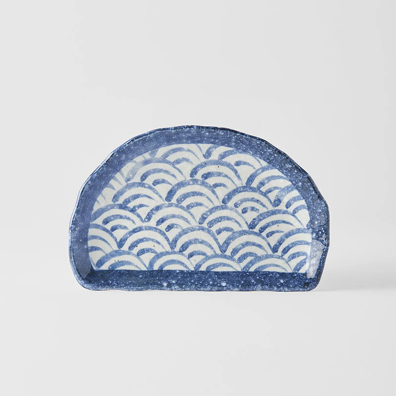 Blue and white ceramic dish with wave pattern on a light gray background
