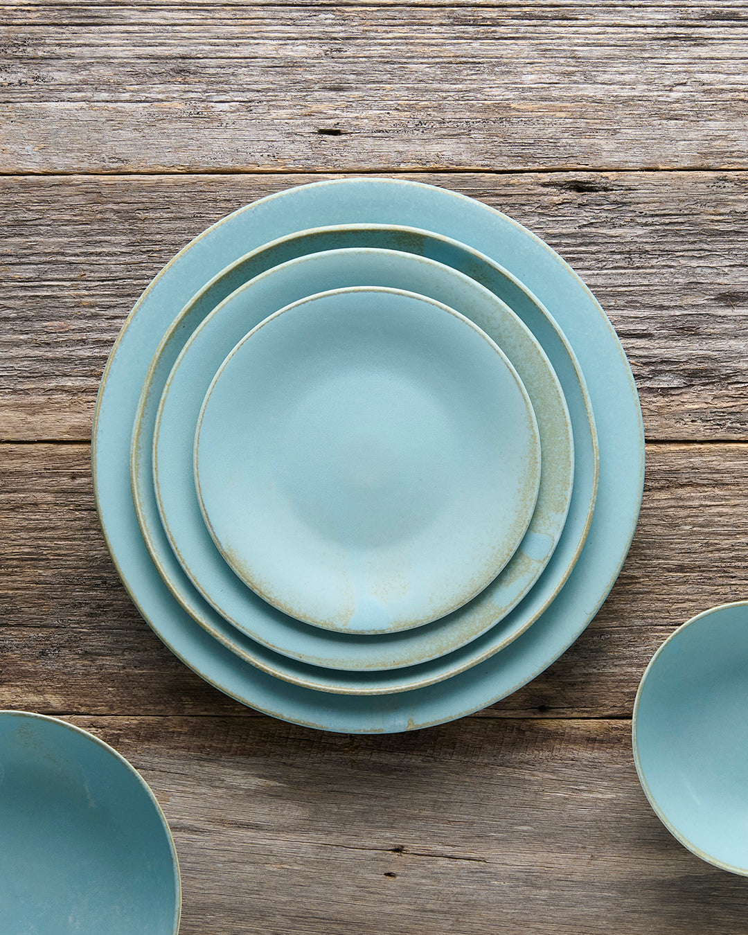 Stack of light blue ceramic plates on a wooden surface