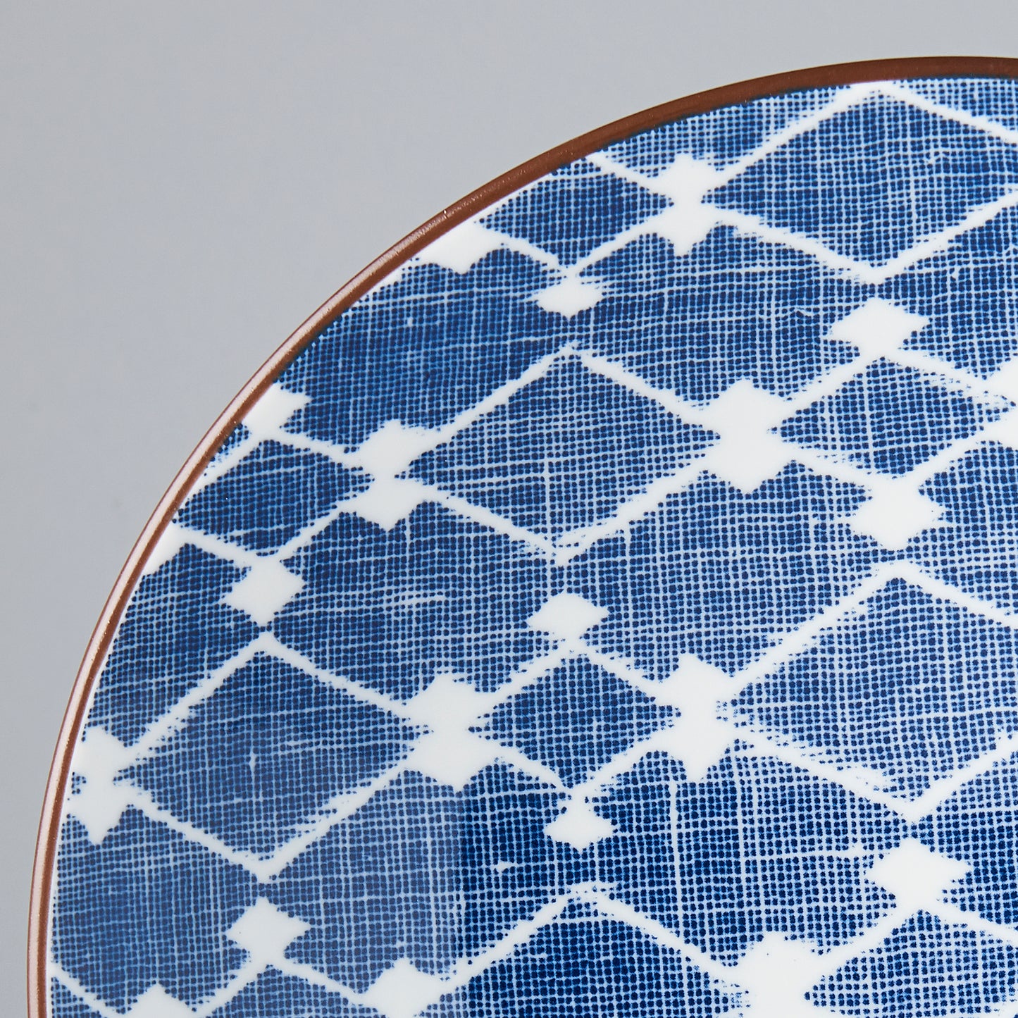 Close-up of a blue and white geometric patterned plate on a gray background