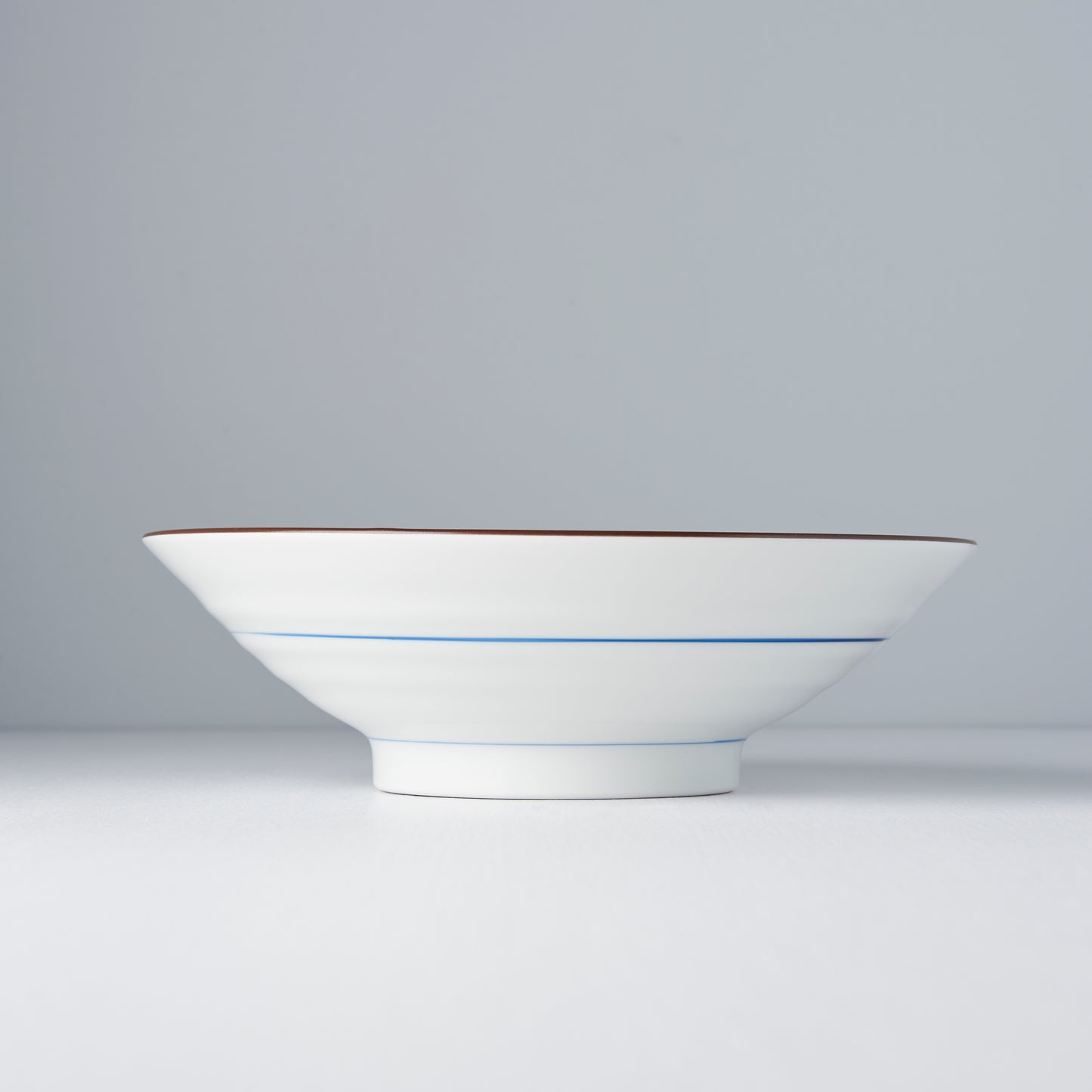 White ceramic bowl with a blue accent on a gray background