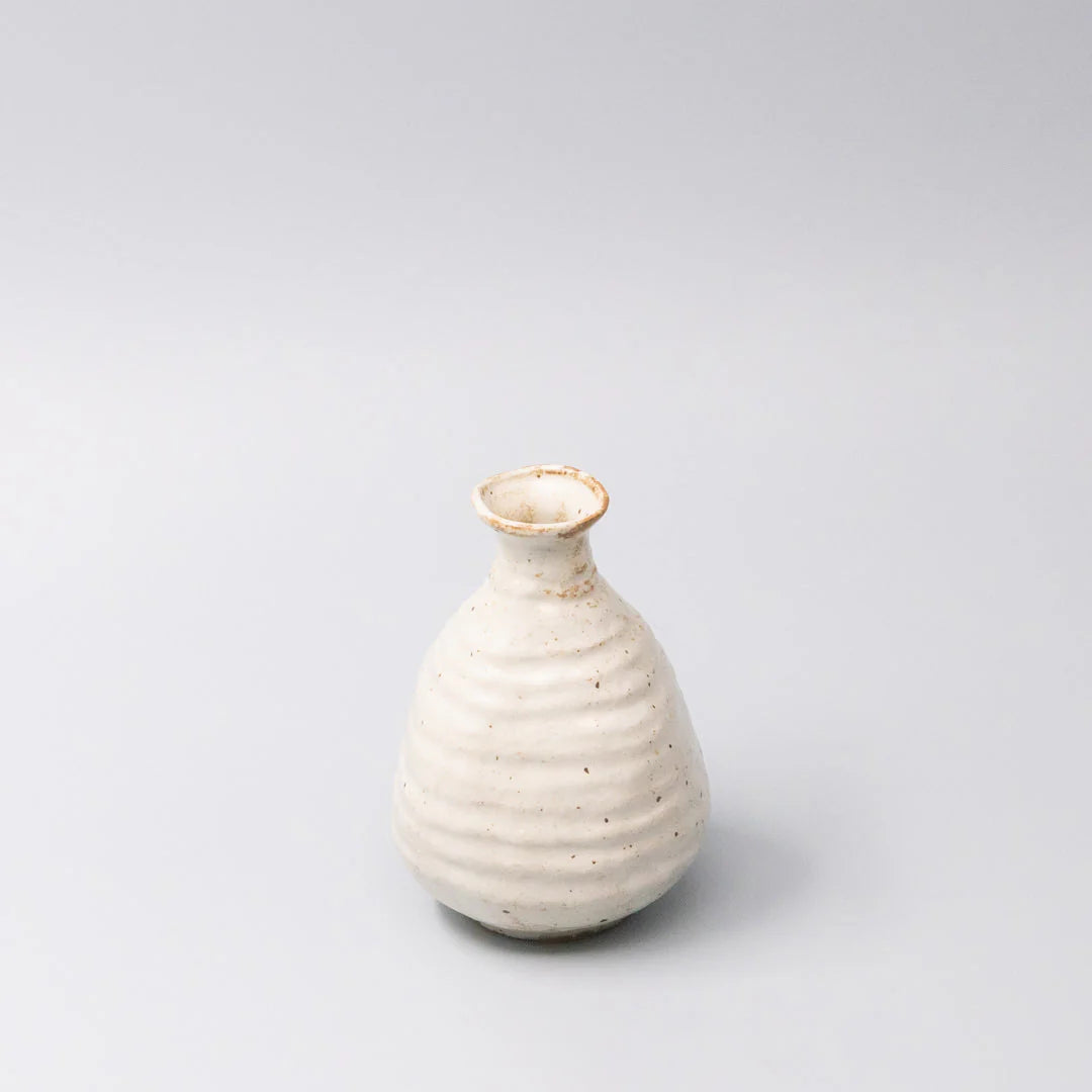 White ceramic vase with gold rim on a light gray background