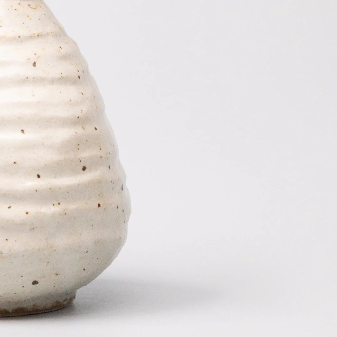 White ceramic vase with textured surface on a light gray background