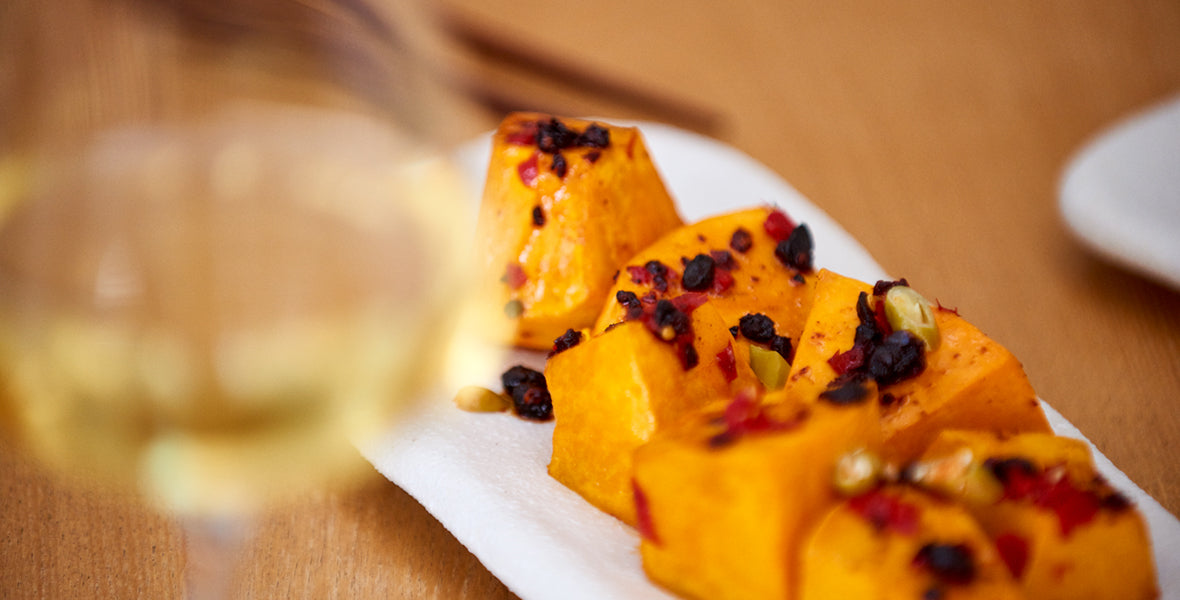 Plated dish of orange-colored food with garnishes on a wooden table.