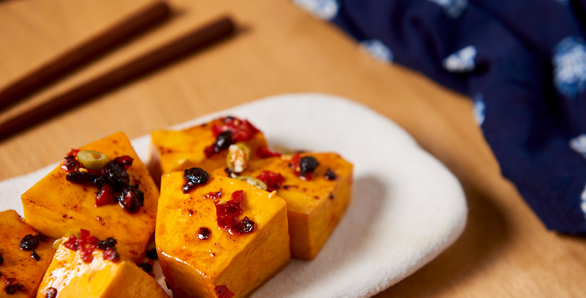 Sliced pumpkin with toppings on a white plate on a wooden surface