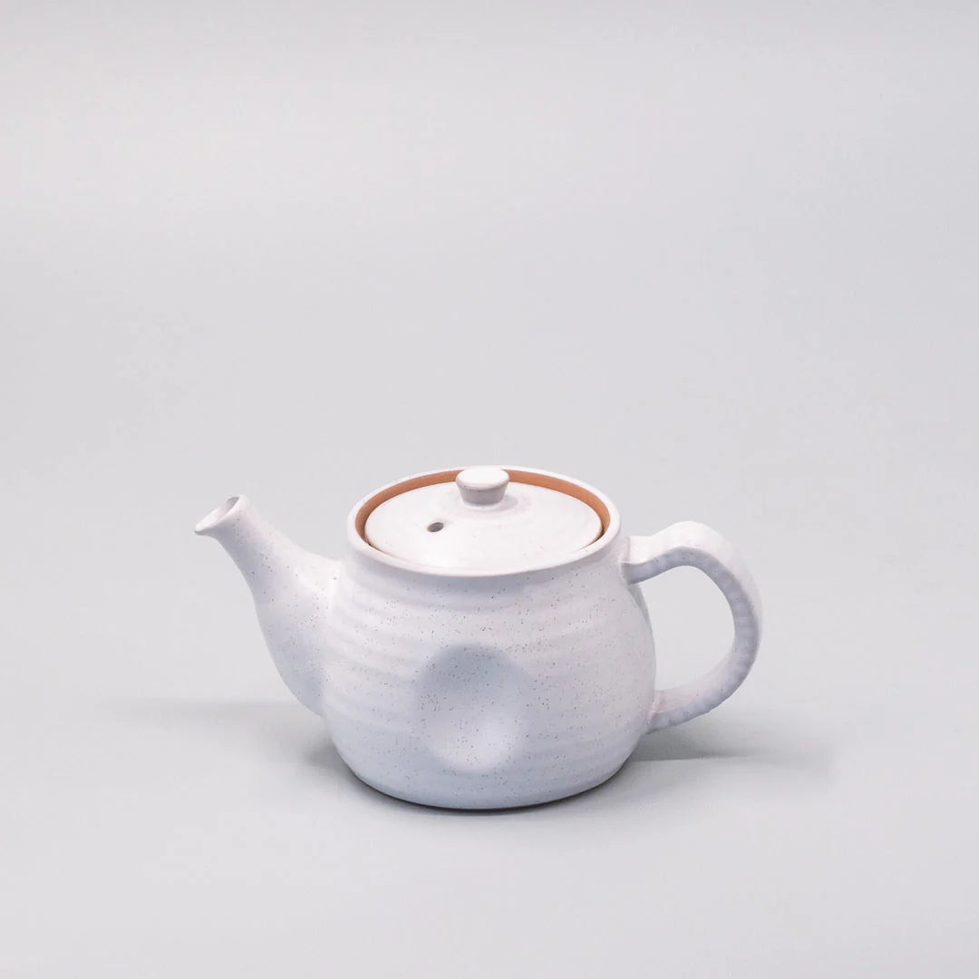 White ceramic teapot on a light gray background