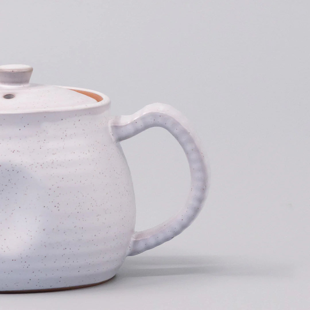 Speckled ceramic teapot on a light gray background