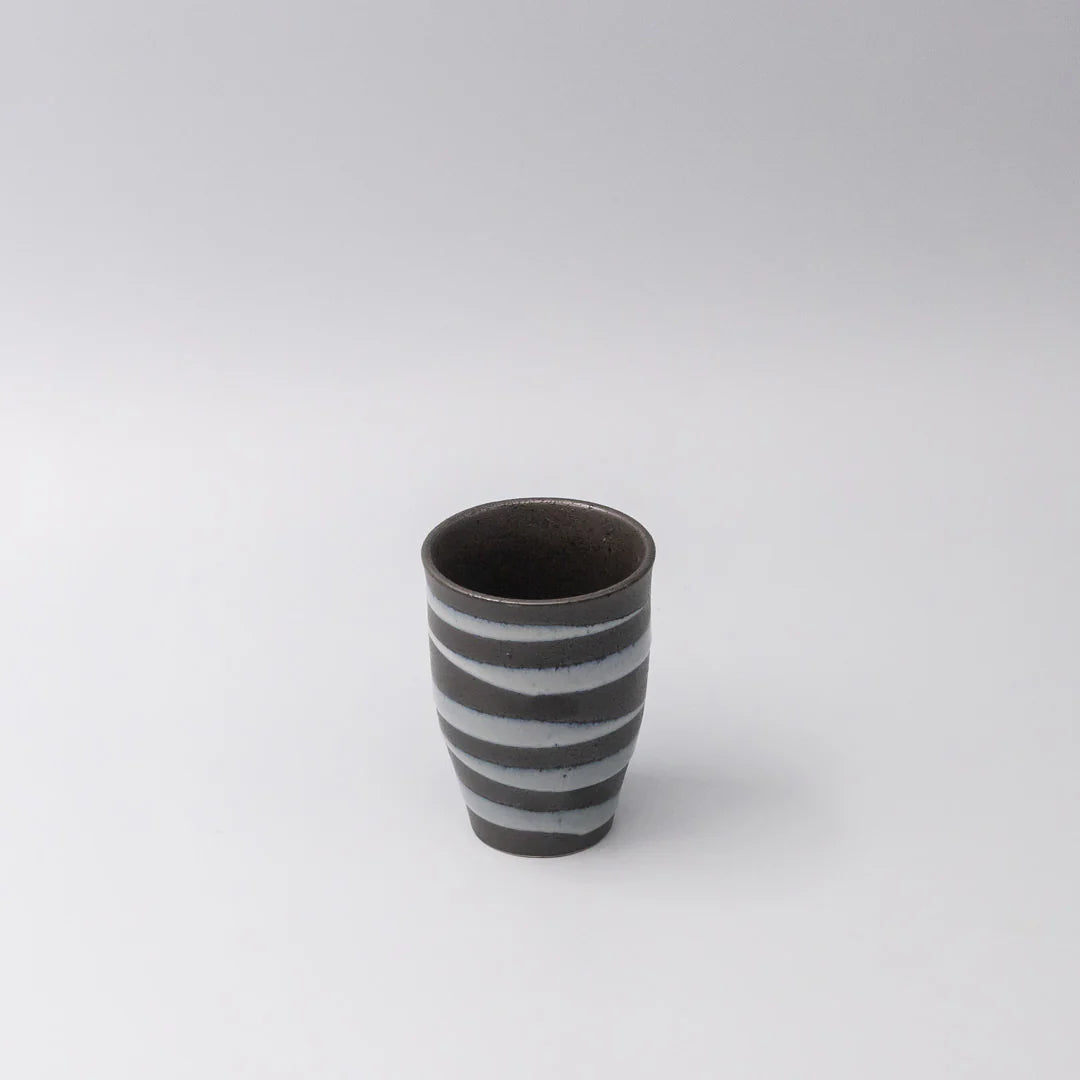 Ceramic cup with black and white stripes on a light gray background