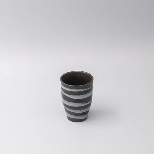 Ceramic cup with black and white stripes on a light gray background