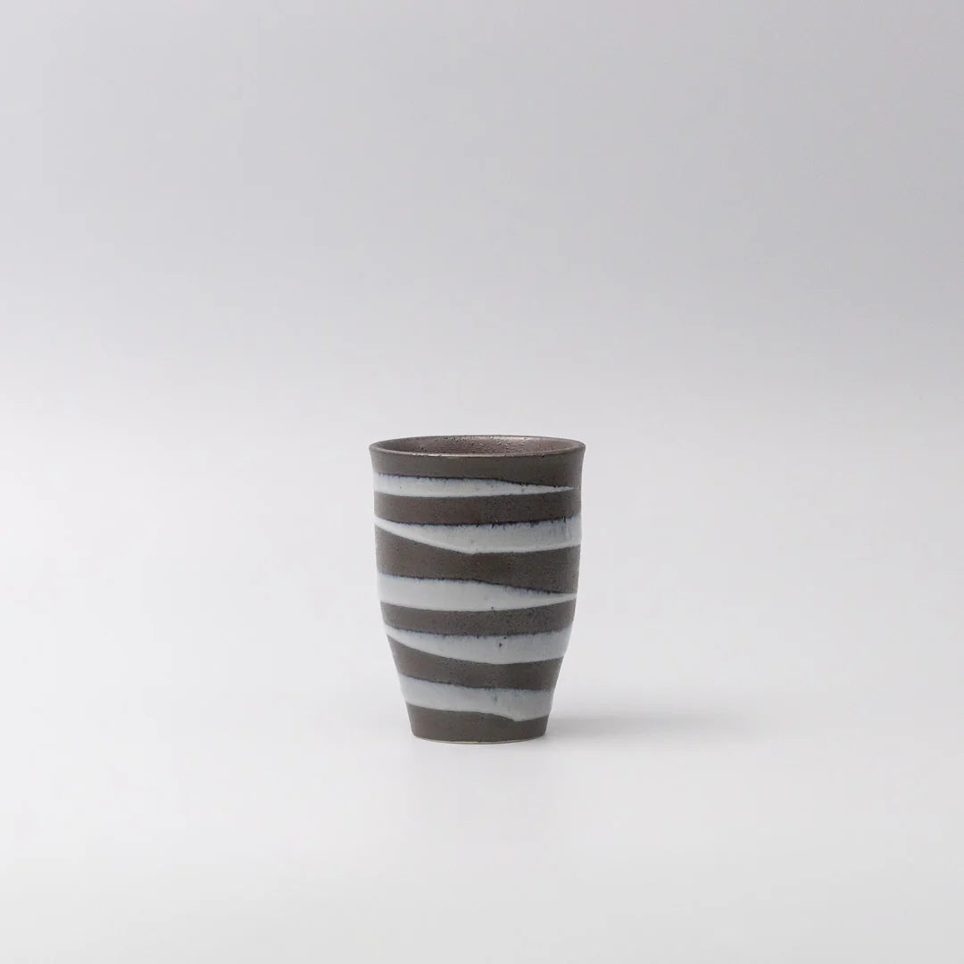 Ceramic cup with black and white stripes on a light gray background