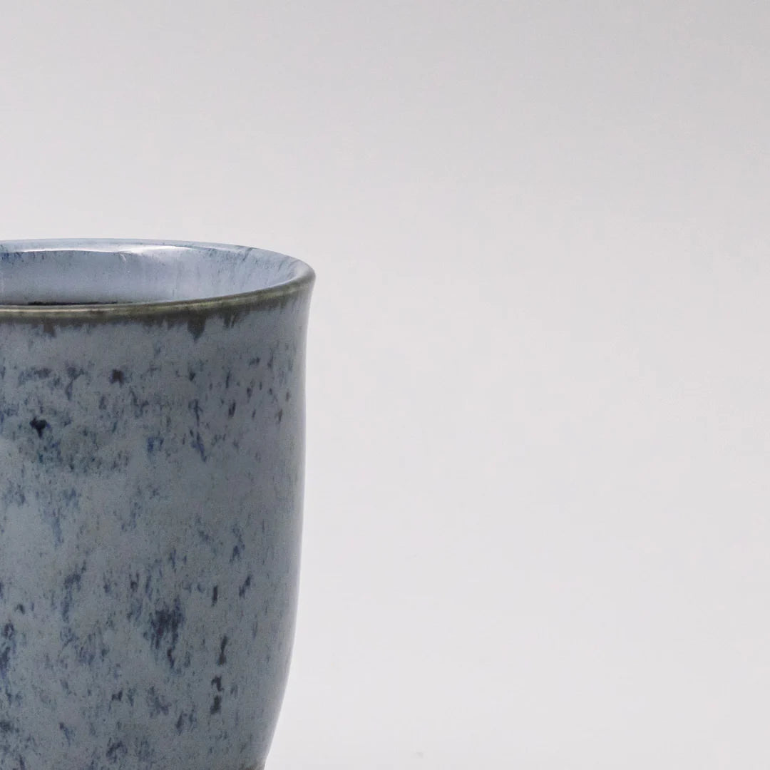 Speckled blue ceramic cup on a white background