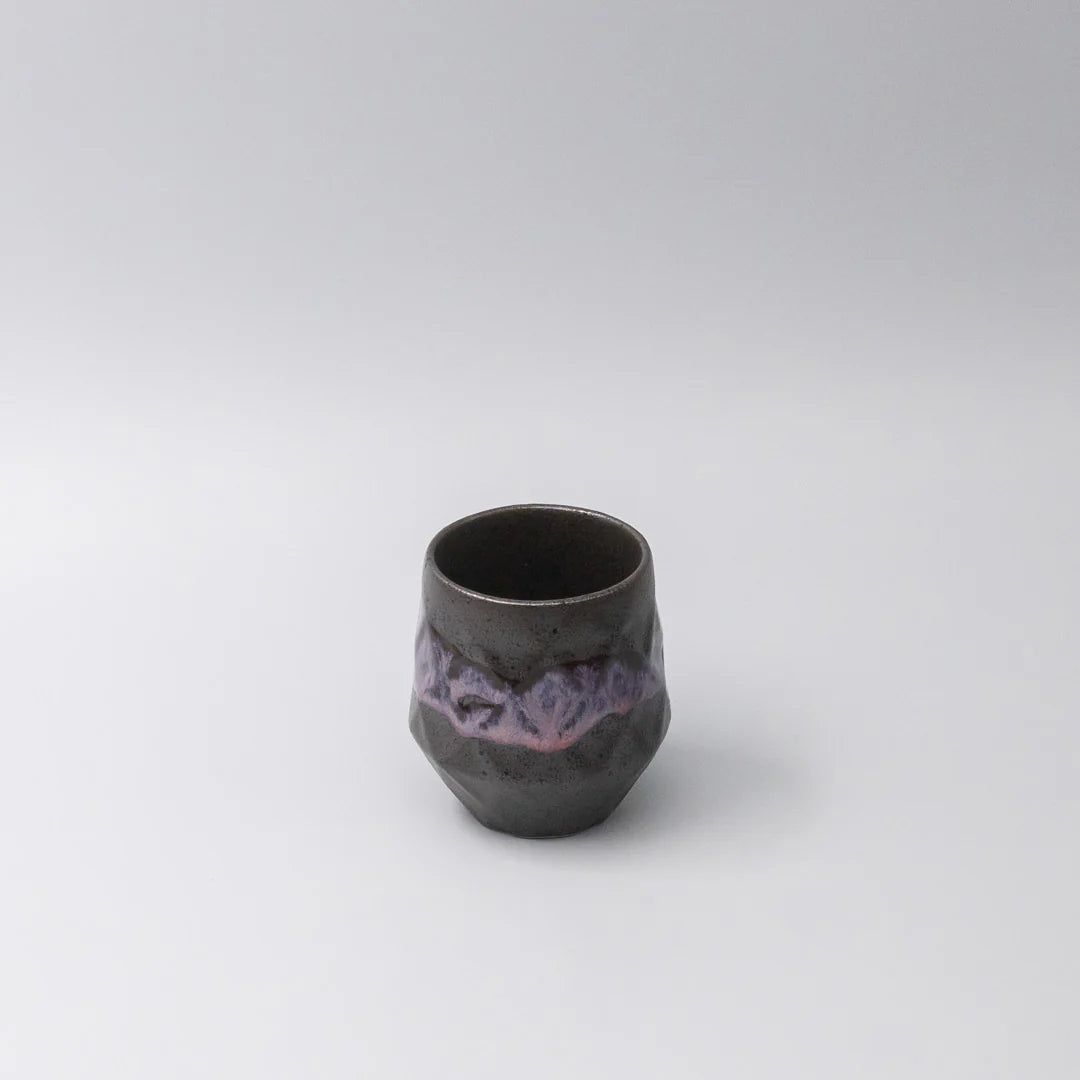 Black ceramic cup with purple interior on a white background