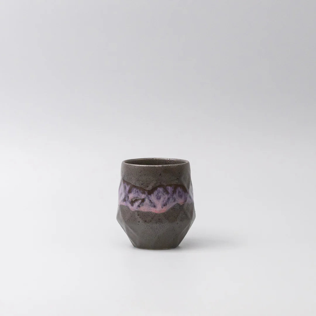 Small ceramic cup with purple interior on a light gray background