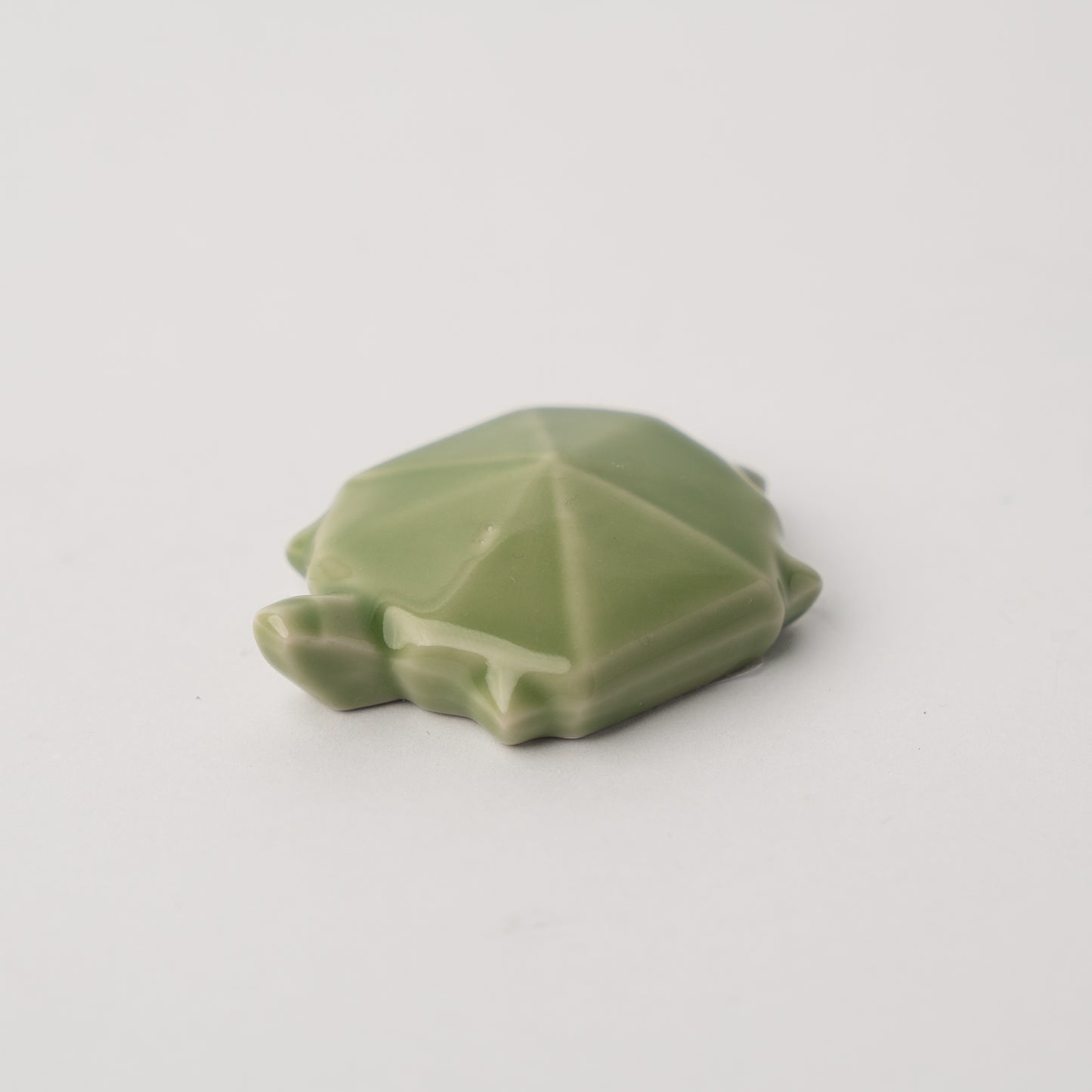 Green ceramic turtle figurine on a light gray background