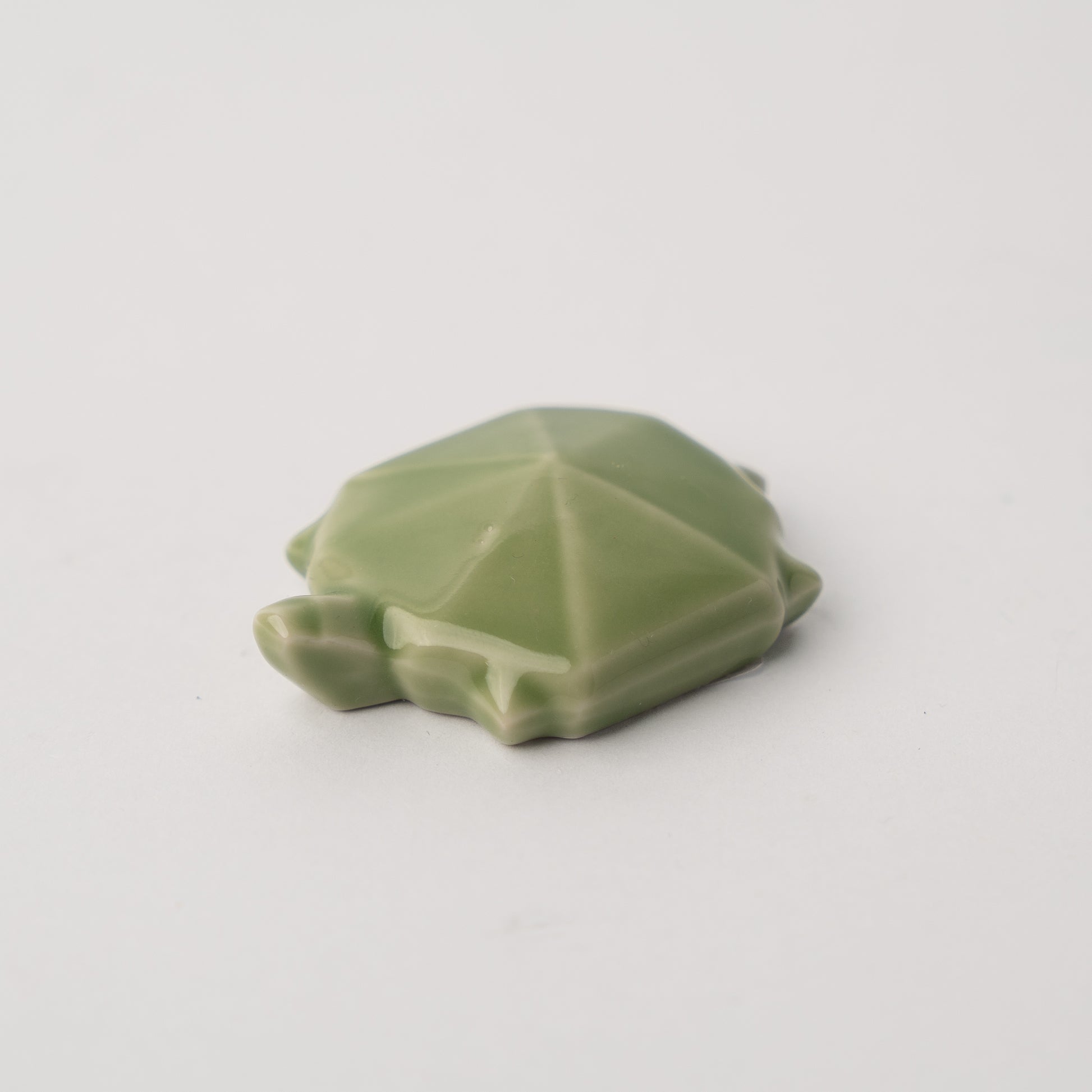 Green ceramic turtle figurine on a light gray background
