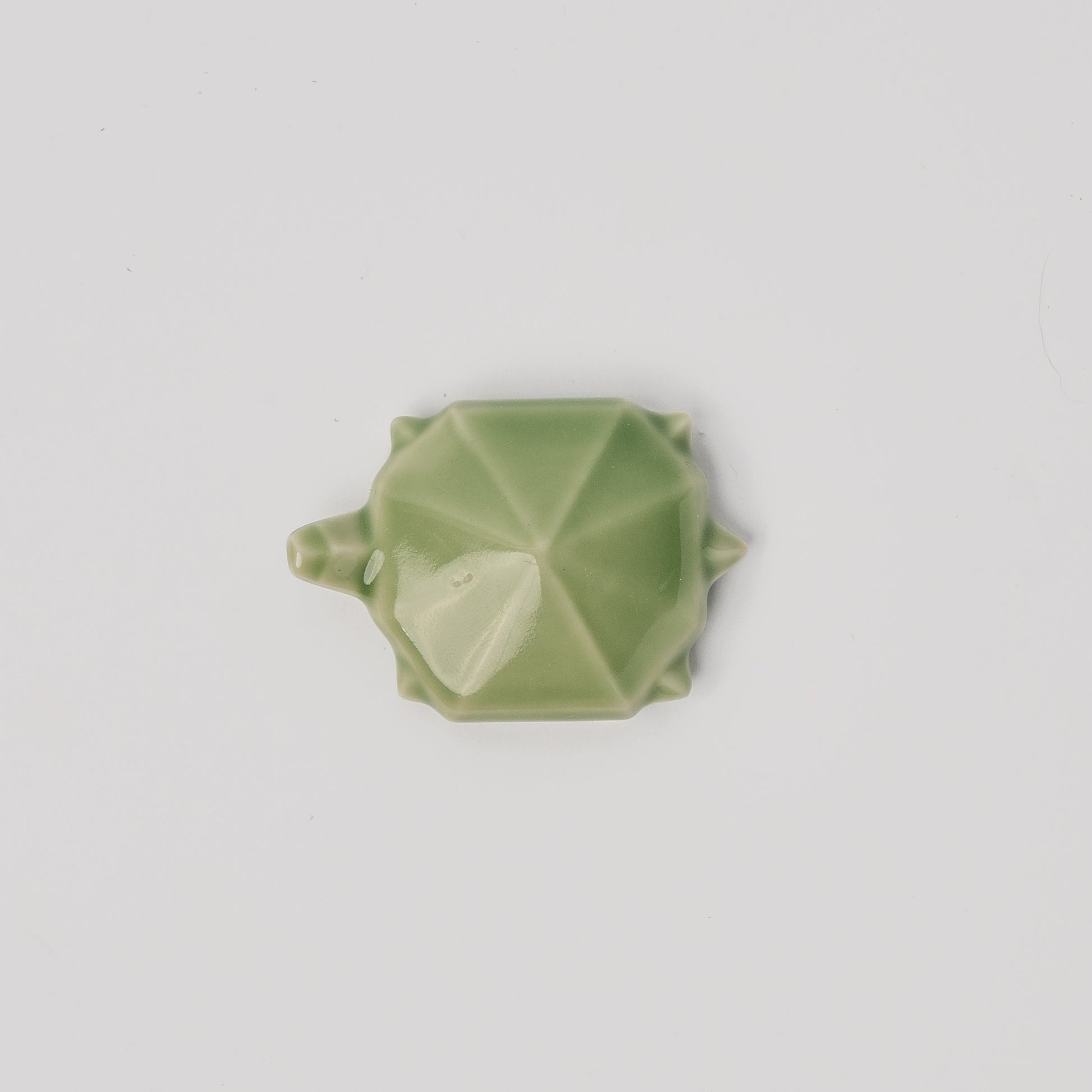 Green geometric object on a light gray background