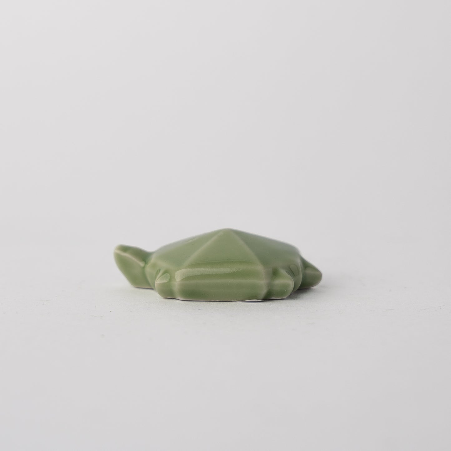 Green ceramic frog on a light gray background