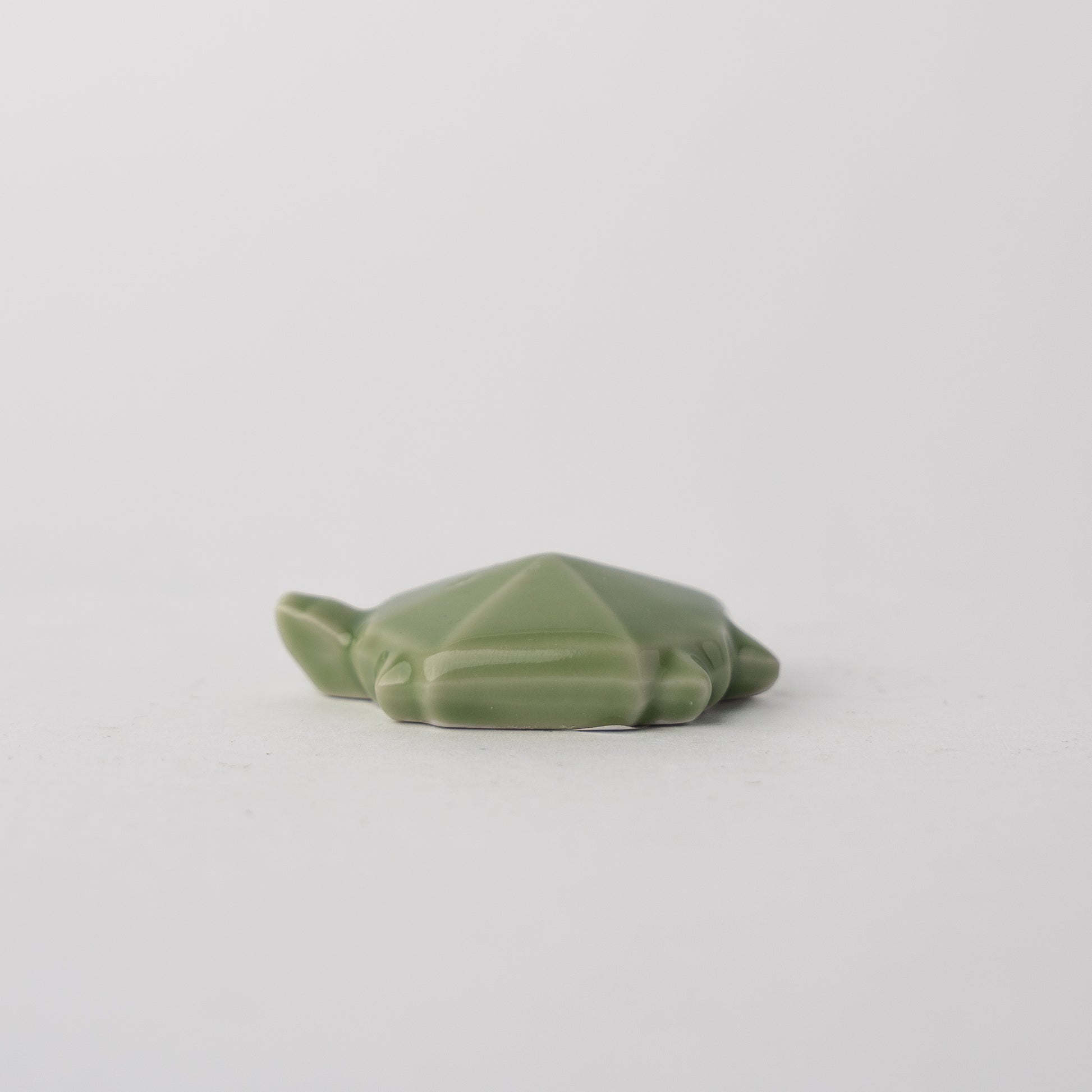 Green ceramic frog on a light gray background