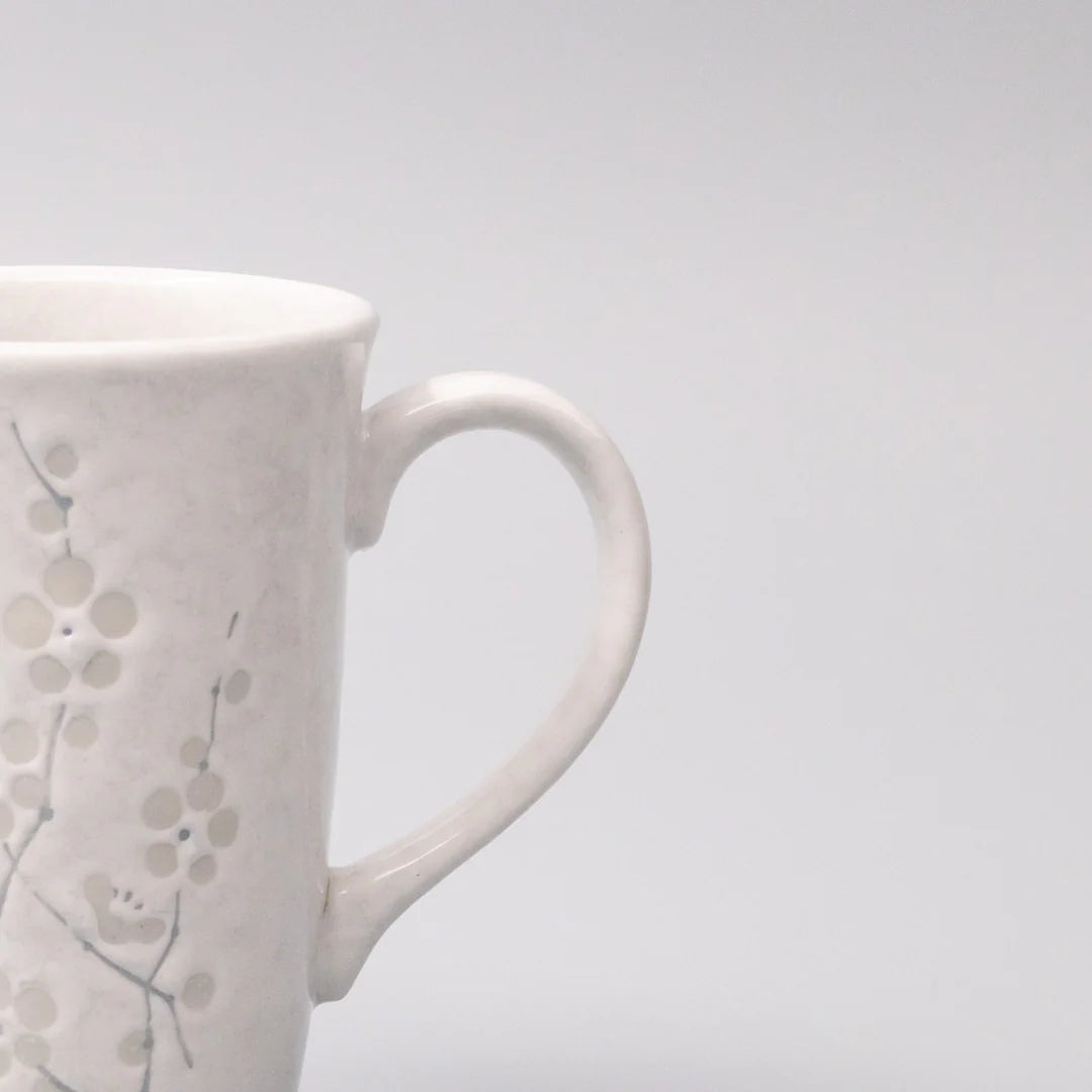 White ceramic mug with floral patterns on a light gray background