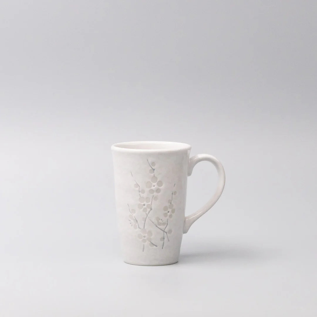 White ceramic mug with embossed design on a light gray background