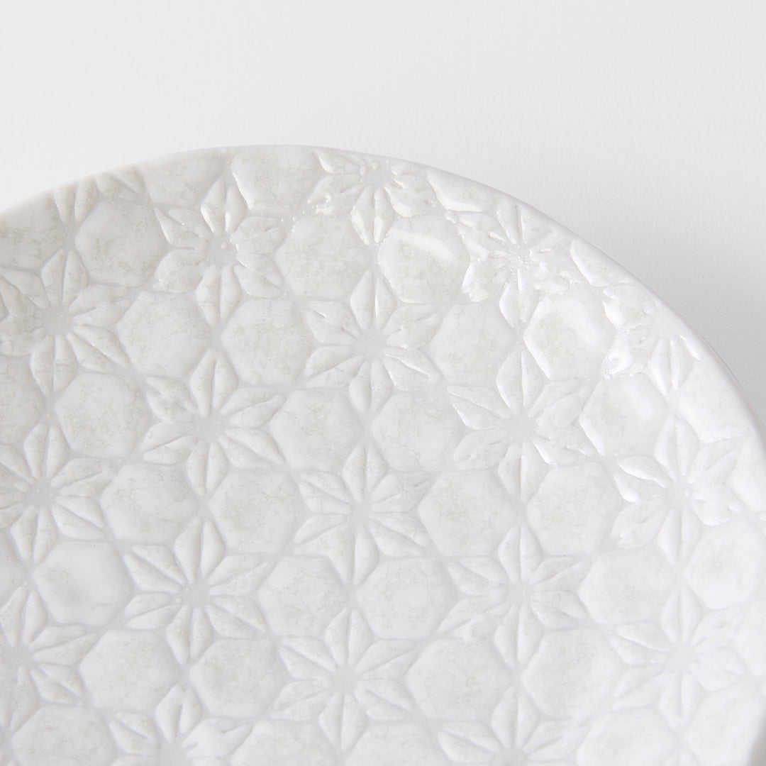 White ceramic plate with a textured pattern on a light gray background